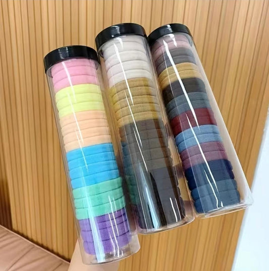 Colorful hair ties in plastic containers displayed on a wooden surface.